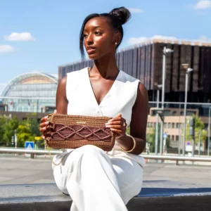 Mulher a segurar a Mala Celine castanha da Dy’Kroché, mostrando o design artesanal em croché e macramé num ambiente urbano.